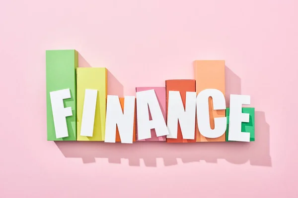 Top view of finance inscription on pink background with color block graph — Stock Photo