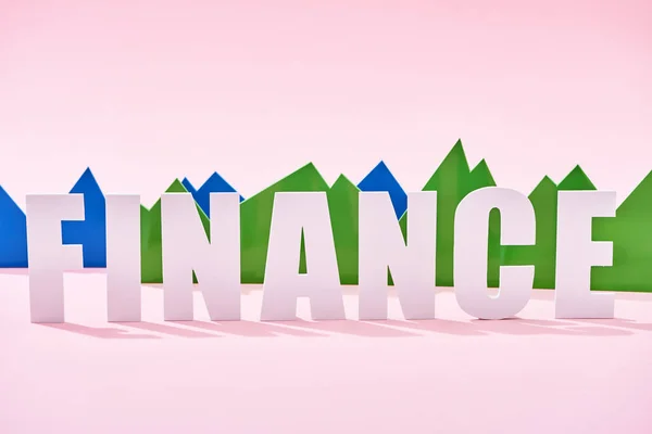 Green and blue statistic graphs behind white finance inscription on pink background — Stock Photo