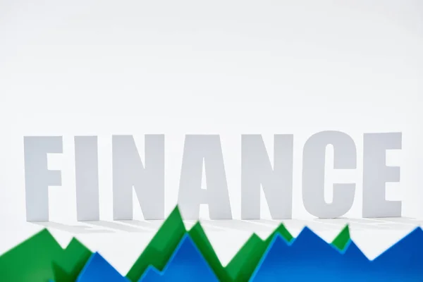 Finance inscription behind green and blue statistic graphs on white background — Stock Photo