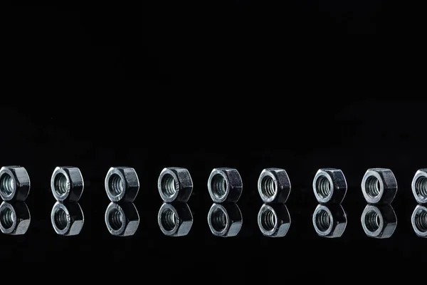 Горизонтальный ряд металлических гаек, изолированных на черном — стоковое фото