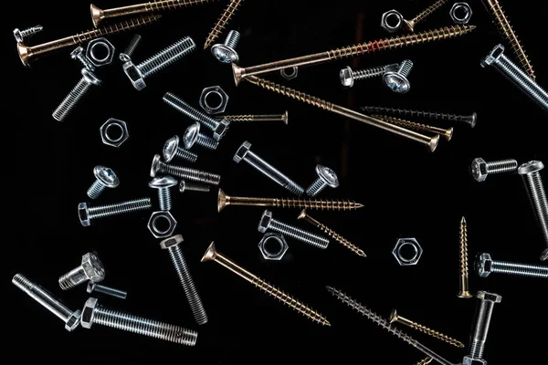 Top view of scattered various screws isolated on black — Stock Photo