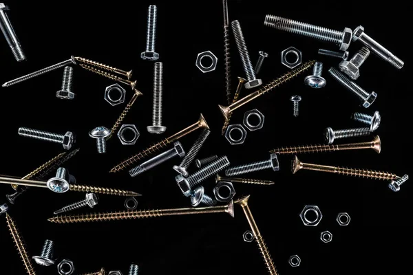 Top view of scattered bolts, nuts and studs isolated on black — Stock Photo