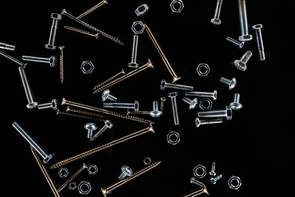 Top view of scattered nuts, bolts and studs isolated on black — Stock Photo