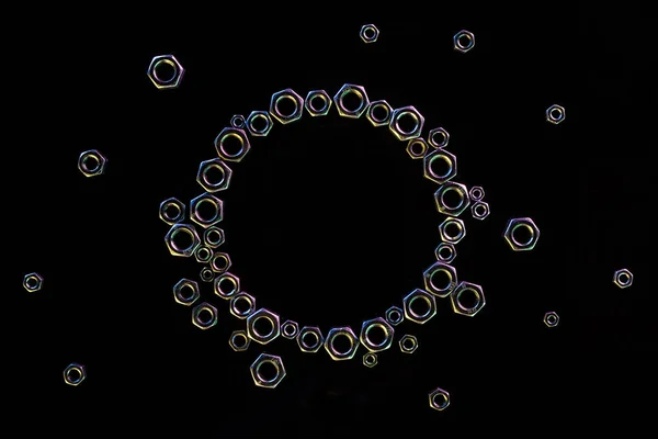 Top view of circle of scattered metal nuts isolated on black — Stock Photo