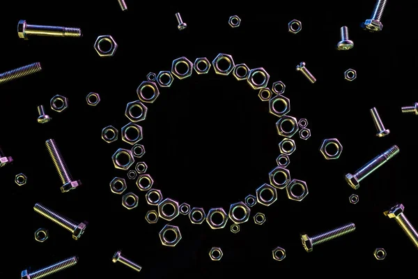 Top view of circle of scattered metal nuts and bolts isolated on black — Stock Photo