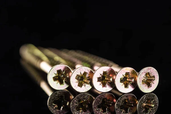 Vue rapprochée des têtes de goujons métalliques isolés sur noir — Photo de stock