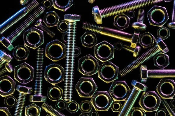 Top view of scattered metallic bolts and nuts isolated on black — Stock Photo