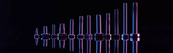 Panoramic shot of shiny purple metallic bolts isolated on black — Stock Photo