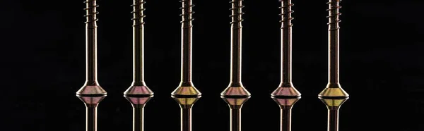 Panoramic shot of new shiny metallic screws row isolated on black — Stock Photo