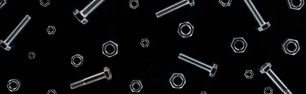 Panoramic shot of scattered metal bolts and nuts pattern isolated on black — Stock Photo