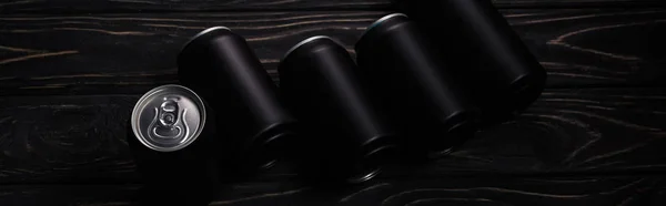 Panoramic shot of black metallic cans of beer on wooden table — Stock Photo