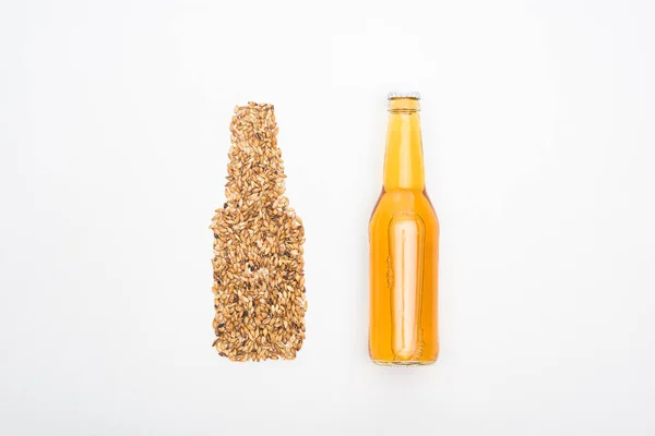 Vue du dessus de la bouteille de bière légère près de grains de blé entier isolés sur blanc — Photo de stock