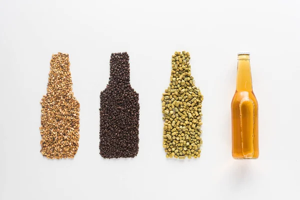 Top view of bottle of light beer near wheat, coffee grains and pressed hop isolated on white — Stock Photo