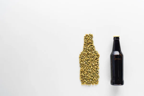 Vue du dessus de la bouteille de bière sombre près du houblon pressé isolé sur blanc — Photo de stock