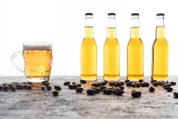 Mug with beer near bottles and coffee grains on brown textured surface — Stock Photo