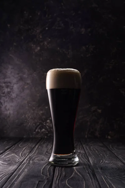 Verre de bière avec mousse sur table en bois — Photo de stock