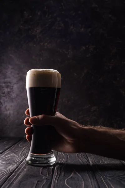 Abgeschnittene Ansicht eines Mannes, der ein Glas Bier auf einem Holztisch trinkt — Stockfoto