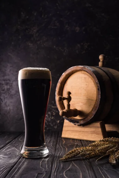 Copo de cerveja perto de pequeno barril com torneira e picos de trigo na mesa de madeira — Fotografia de Stock