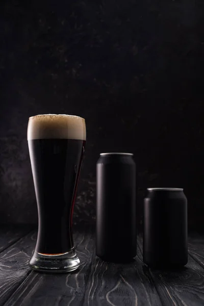 Latas e copo de cerveja na mesa de madeira — Fotografia de Stock