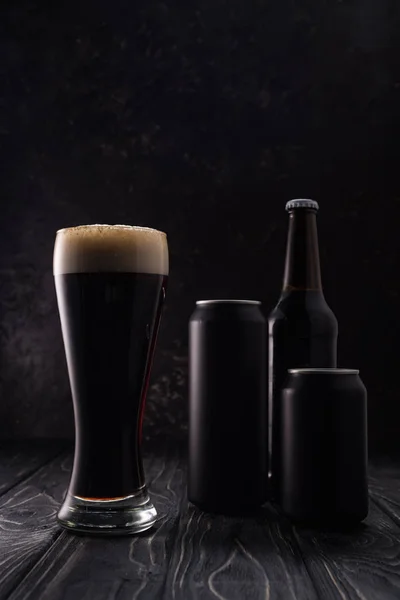 Bottiglia, lattine e bicchiere di birra sul tavolo di legno — Foto stock