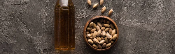 Panoramic shot of bottle of light beer with pistachios on brown textured surface — Stock Photo