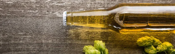 Vista superior de la cerveza en botella con el salto verde en la mesa de madera, tiro panorámico - foto de stock