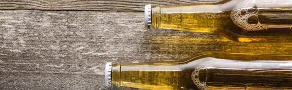 Top view of beer in bottles on wooden background, panoramic shot — Stock Photo