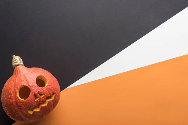 Vue de dessus de fantasmagorique citrouille Halloween sur fond orange, blanc et noir — Photo de stock
