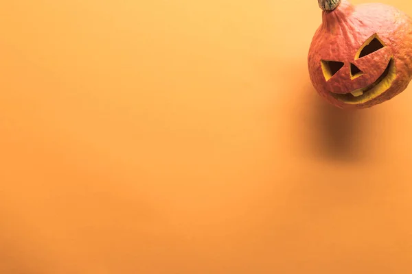 Vista superior de la calabaza de Halloween tallada sobre fondo naranja - foto de stock