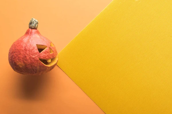 Вид зверху на різьблений гарбуз Хеллоуїн на помаранчевому та жовтому тлі — стокове фото
