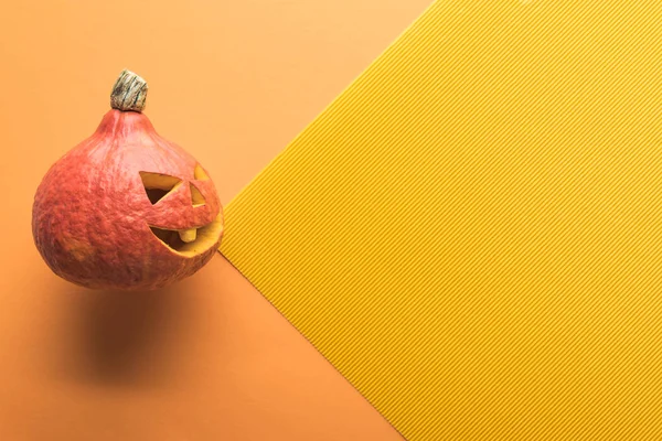 Vista superior da abóbora de Halloween esculpida em fundo laranja e amarelo — Fotografia de Stock