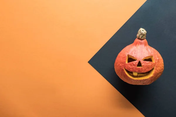 Vista superior de la calabaza de Halloween tallada sobre fondo naranja y negro - foto de stock