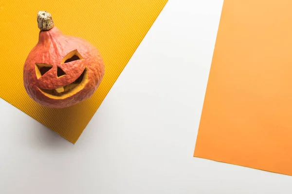 Vista superior de la calabaza de Halloween sobre fondo blanco y naranja - foto de stock