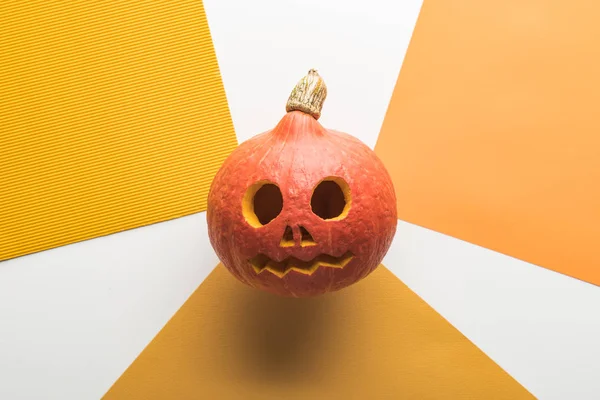 Draufsicht auf Halloween-Kürbis auf weißem und orangefarbenem Hintergrund — Stockfoto