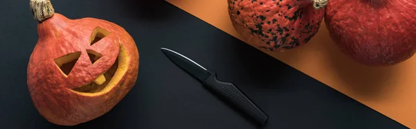 Panoramic shot of Halloween pumpkins with knife on black background — Stock Photo