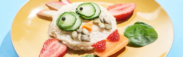 Nahaufnahme des Tellers mit ausgefallenem Gesicht aus Lebensmitteln für das Kinderfrühstück auf blauem Hintergrund, Panoramaaufnahme — Stockfoto