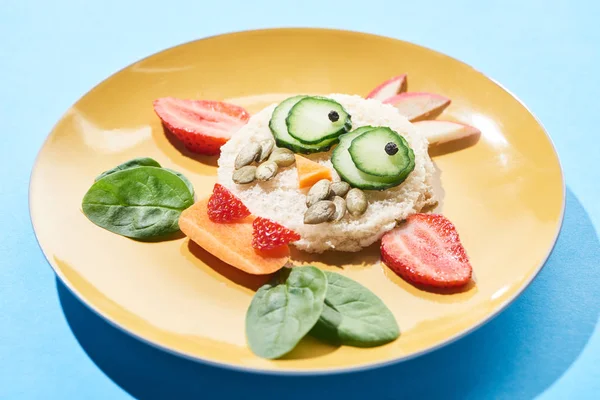 Vista ravvicinata del piatto con fantasia viso fatto di cibo per bambini colazione su sfondo blu — Foto stock