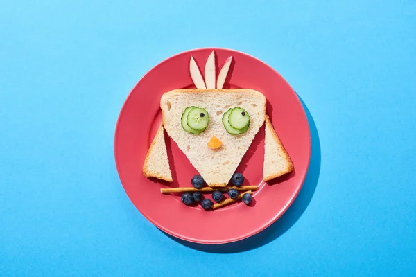 Вид зверху на тарілку з вишуканою пташкою з їжі для дитячого сніданку на синьому фоні — стокове фото