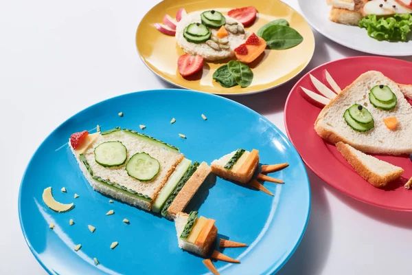 Plates with fancy animals and rocket made of food for childrens breakfast on white background — Stock Photo