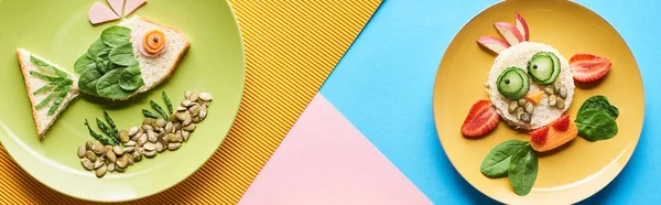 Top view of plates with fancy animals made of food on blue, yellow and pink background — Stock Photo