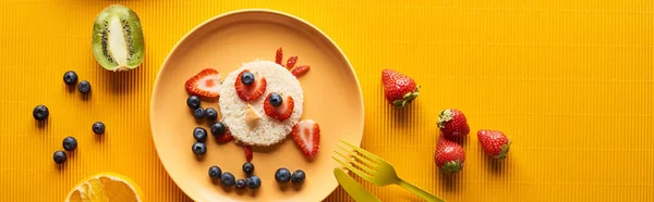 Top view of plate with fancy animal made of food on colorful orange background, panoramic shot — Stock Photo