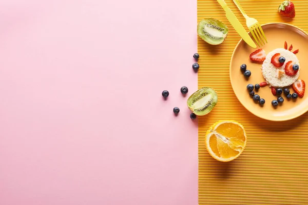 Vue de dessus de l'assiette avec animal de fantaisie fait de nourriture pour le petit déjeuner des enfants près de couverts sur fond orange et rose — Photo de stock