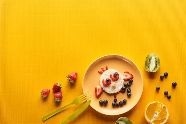 Vista superior da placa com animal de fantasia feito de alimentos perto de talheres no fundo laranja colorido — Fotografia de Stock