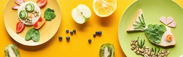 Vista superior de platos con animales de lujo hechos de comida sobre fondo naranja colorido, plano panorámico - foto de stock