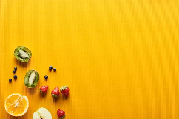Top view of strawberry, blueberry, kiwi and orange on colorful orange background — Stock Photo