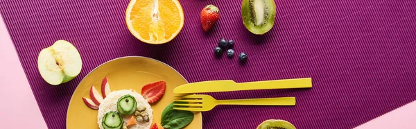 Top view of plate with fancy cow made of food near fruits on purple background, panoramic shot — Stock Photo