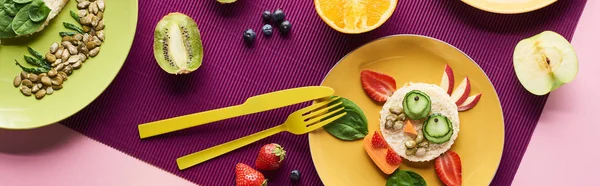 Vue de dessus des assiettes avec des animaux de fantaisie faits de nourriture près des fruits sur fond violet, vue panoramique — Photo de stock