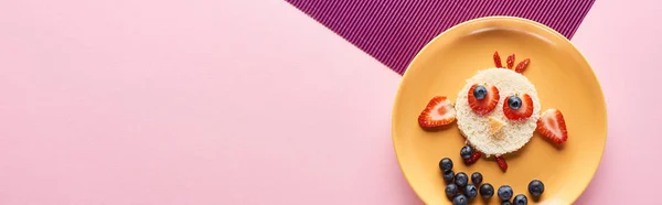 Вид сверху на тарелку с причудливой птицей из еды на розовом и фиолетовом фоне — стоковое фото