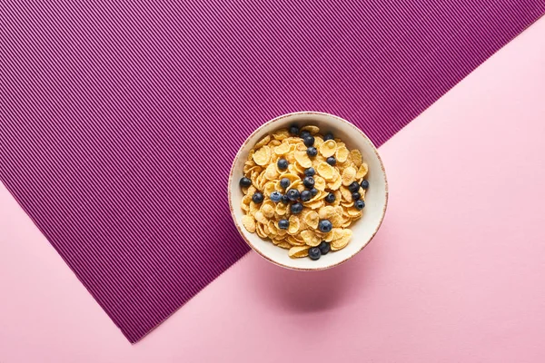 Vista dall'alto della ciotola con cereali per la colazione e mirtillo su sfondo viola e rosa — Foto stock