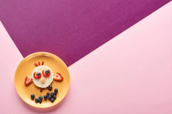 Vista superior da placa com pássaro extravagante feito de comida em fundo rosa e roxo — Fotografia de Stock